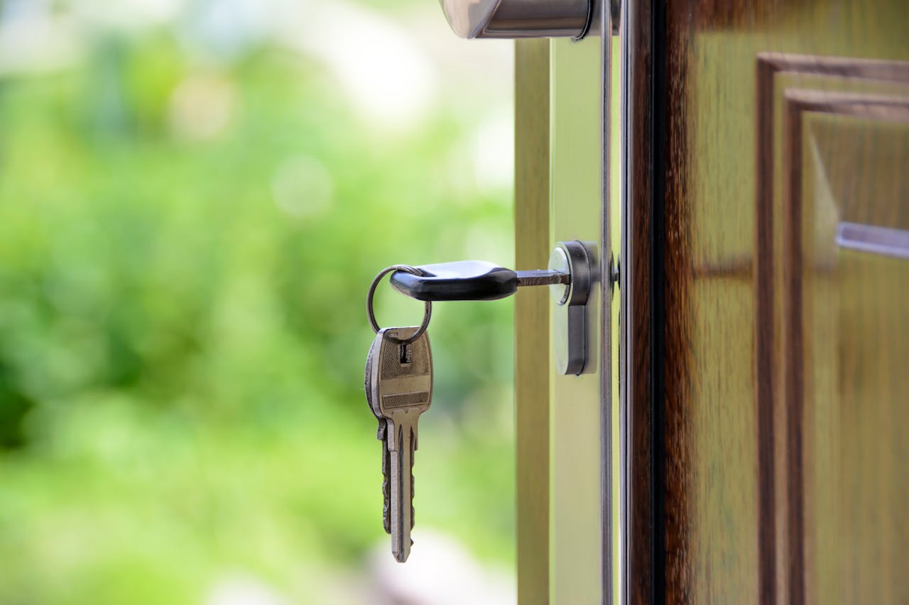 hero-img-01 Key inserted in door lock against a blurred green background, symbolizing security and real estate.