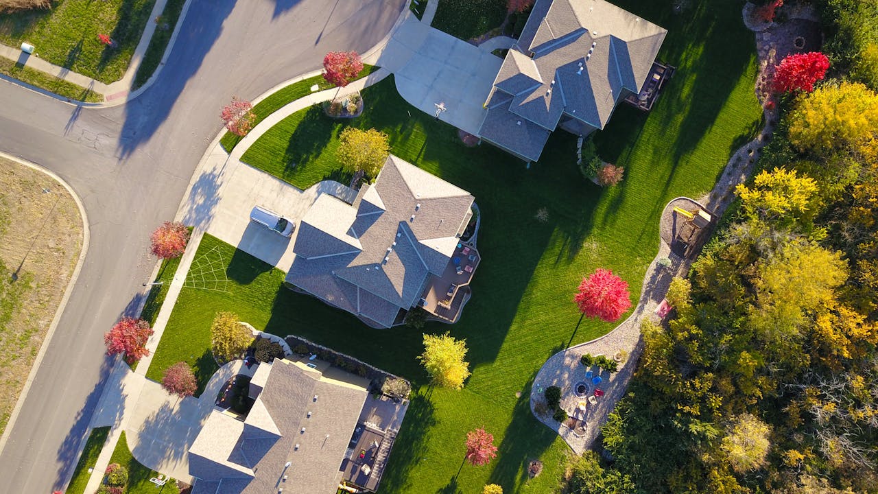our-services-1 A picturesque aerial view showcasing suburban homes with vibrant gardens and tree-lined streets.