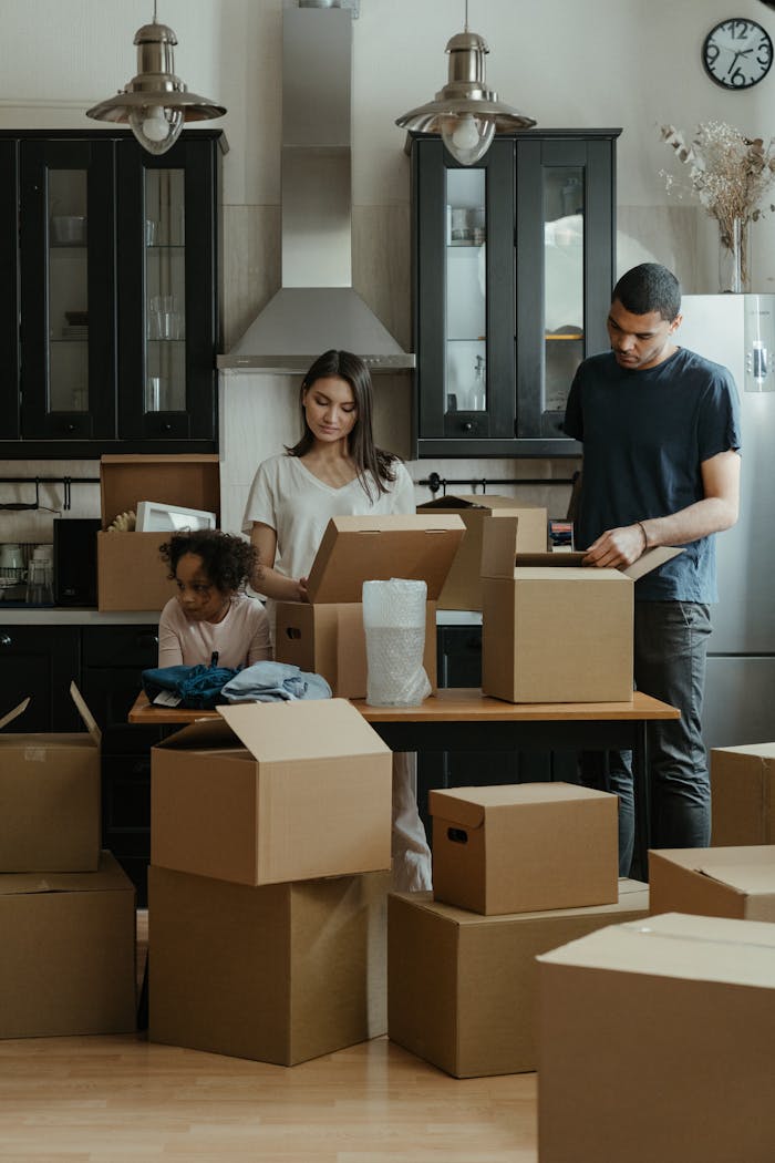 gallery-1 Family unpacking boxes together in a modern kitchen after moving into a new home.