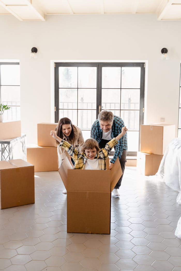 services-02 Happy family celebrating move into new home with unpacked boxes.