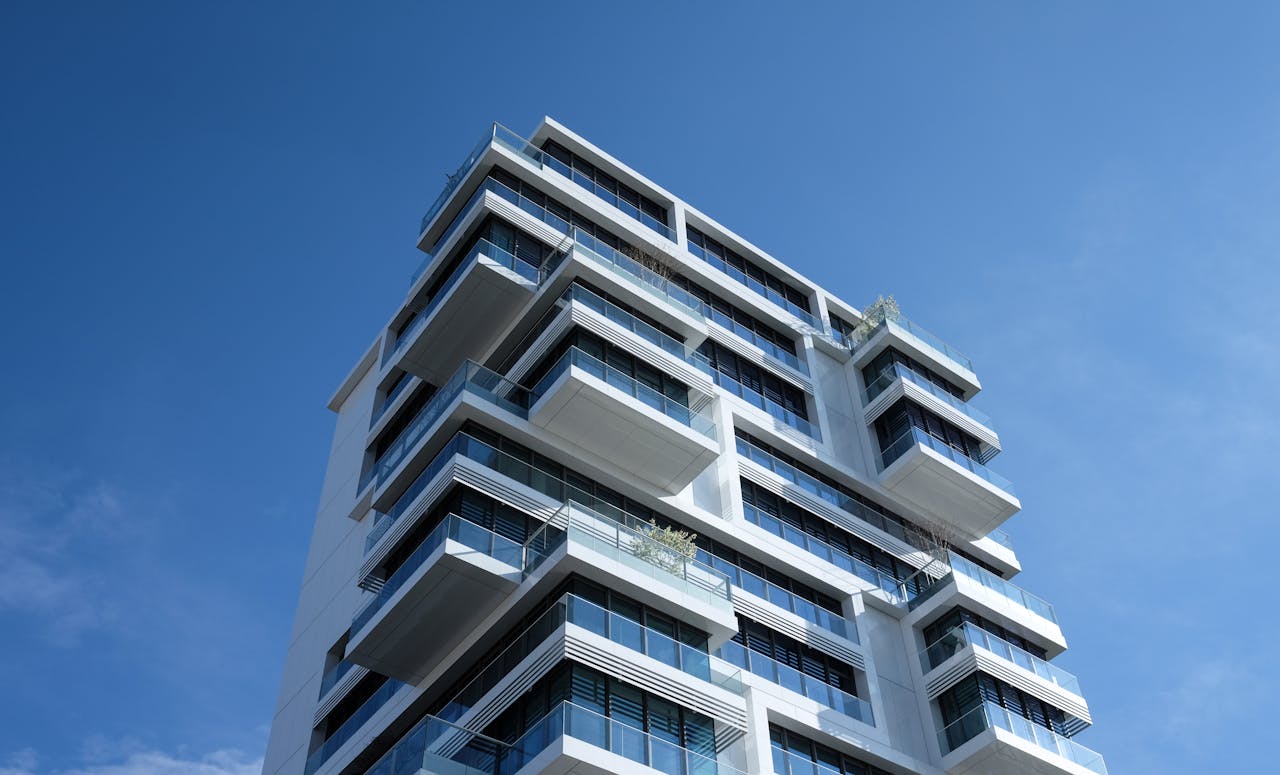 our-services-3 Striking low-angle shot of a modern condominium with unique balcony design and clear blue sky.
